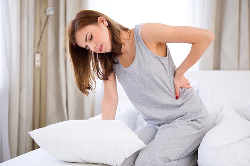 Women with Back Pain leaning on bed