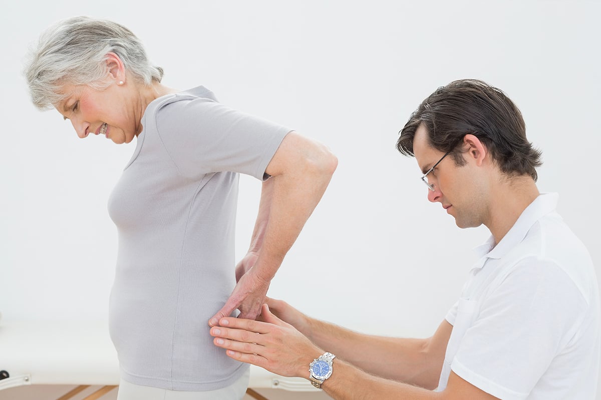 Doctor inspecting older woman's lower back