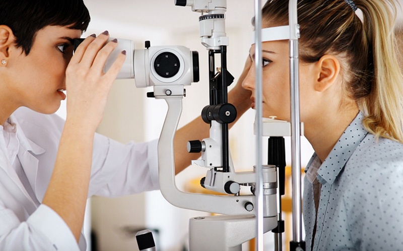 female eye doctor examing patient's eyes