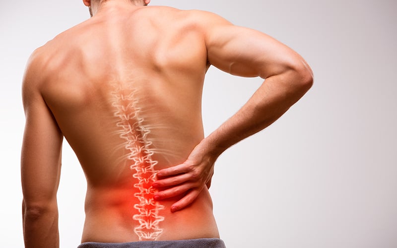 Man clutching pained back with an image of an irritated spine overlaid over the back