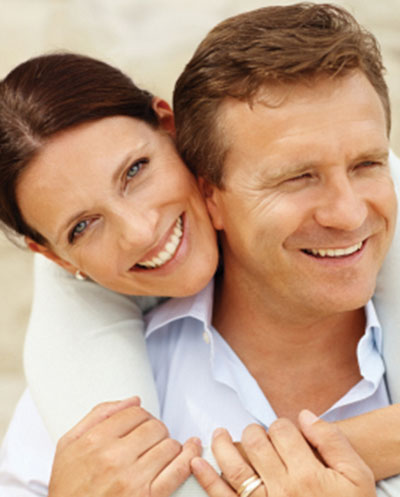 Older woman happily wrapping her arms around her smiling husband's neck