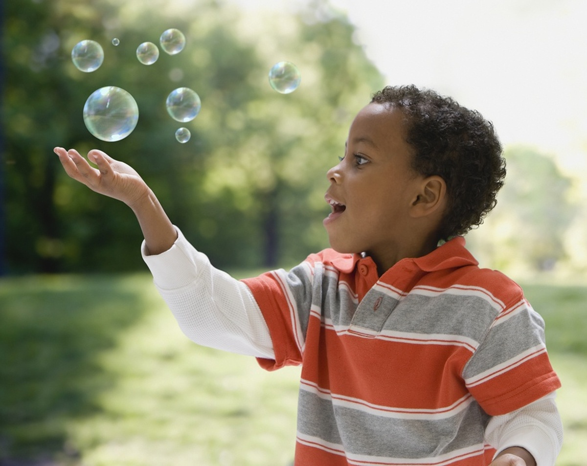 bigstock-African-boy-catching-bubbles-73328053-1